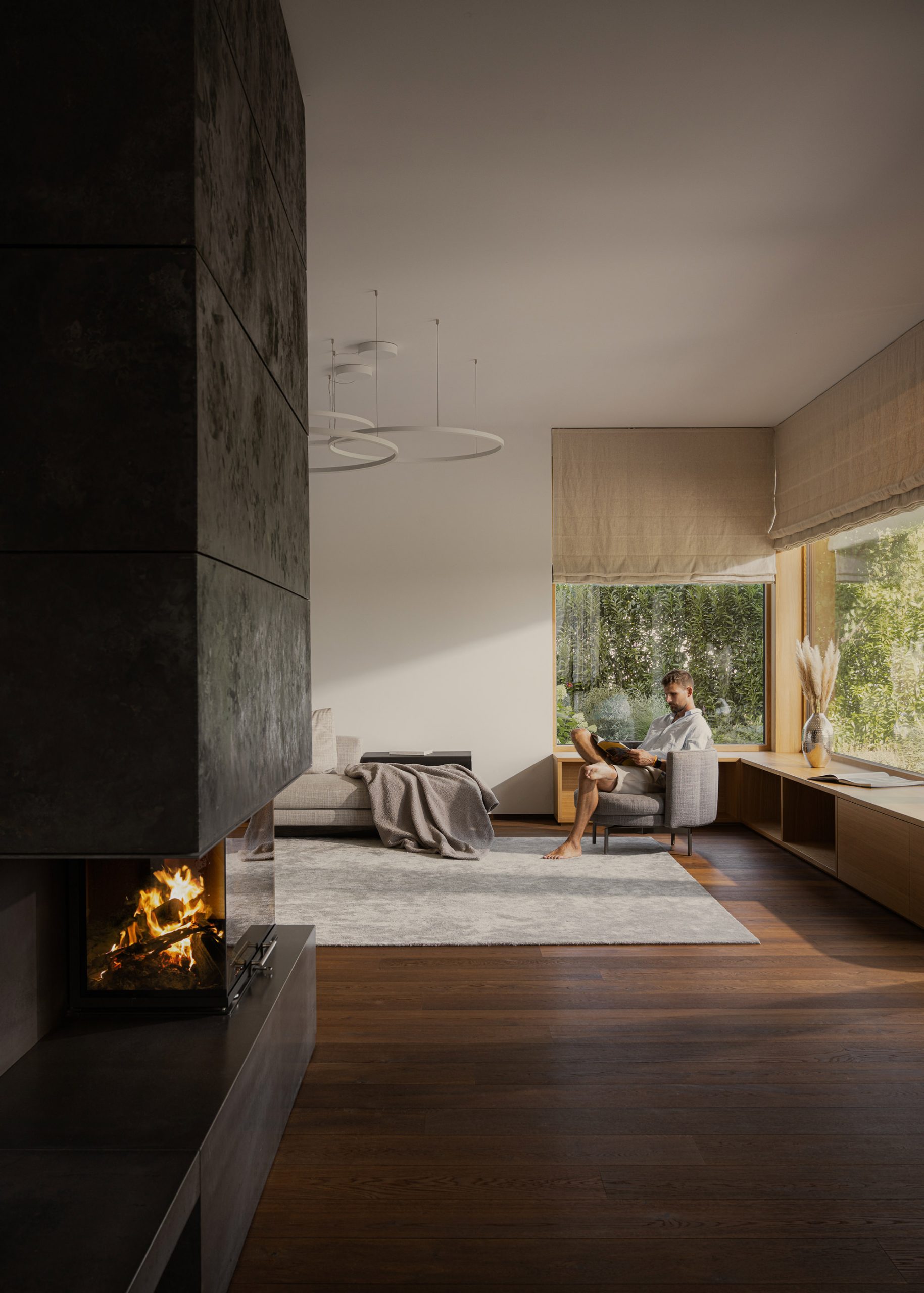 Wohnbereich mit Kamin in dem ein Mann eine Zeitschrift auf einem Relaxsessel liest