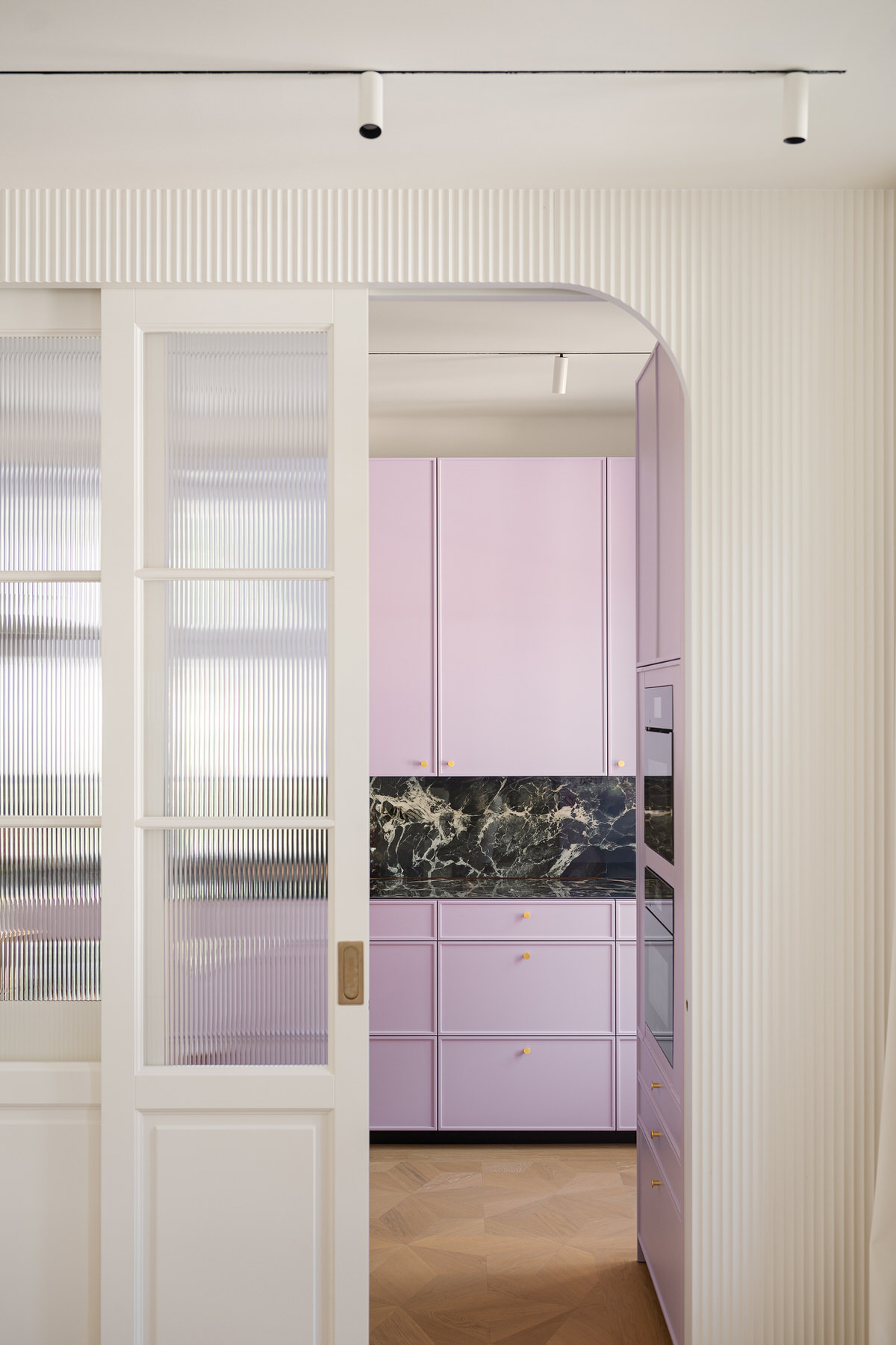 Abgerundeter Durchgang zur Küche. Die Schiebetüre ist halb geöffnet sodass man die Küche sehen kann.