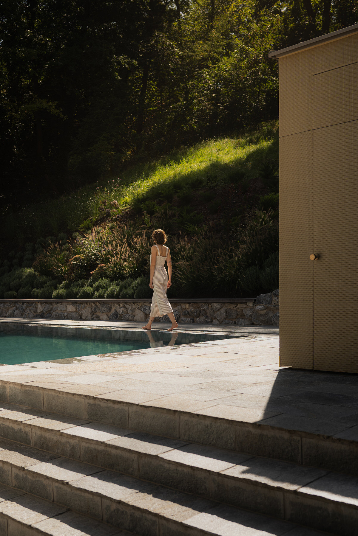 Eine Frau geht neben dem Pool entlang.