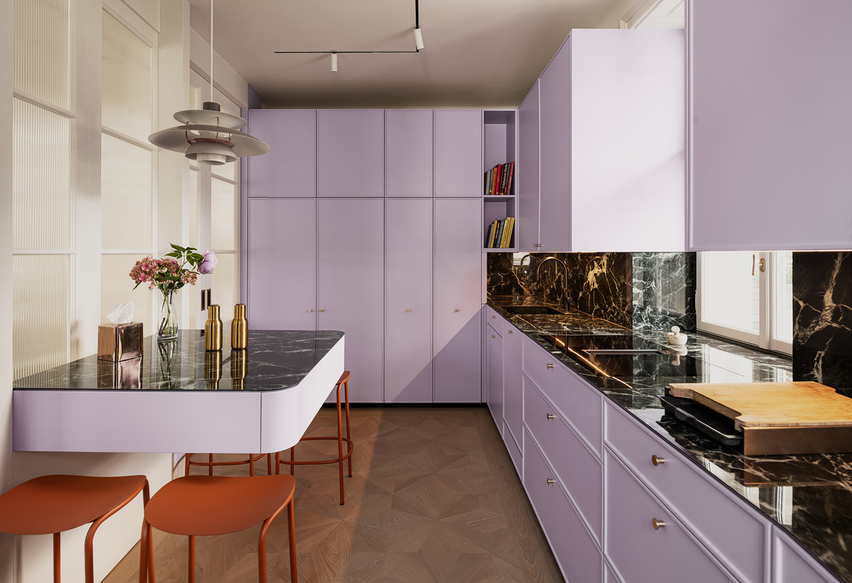 Komplettaufnahme der Küche mit einer Küchenzeile auf der rechten Seite. Links befinden sich eine schwebend wirkende Bar-Sitzgelegenheit und der Durchgang.