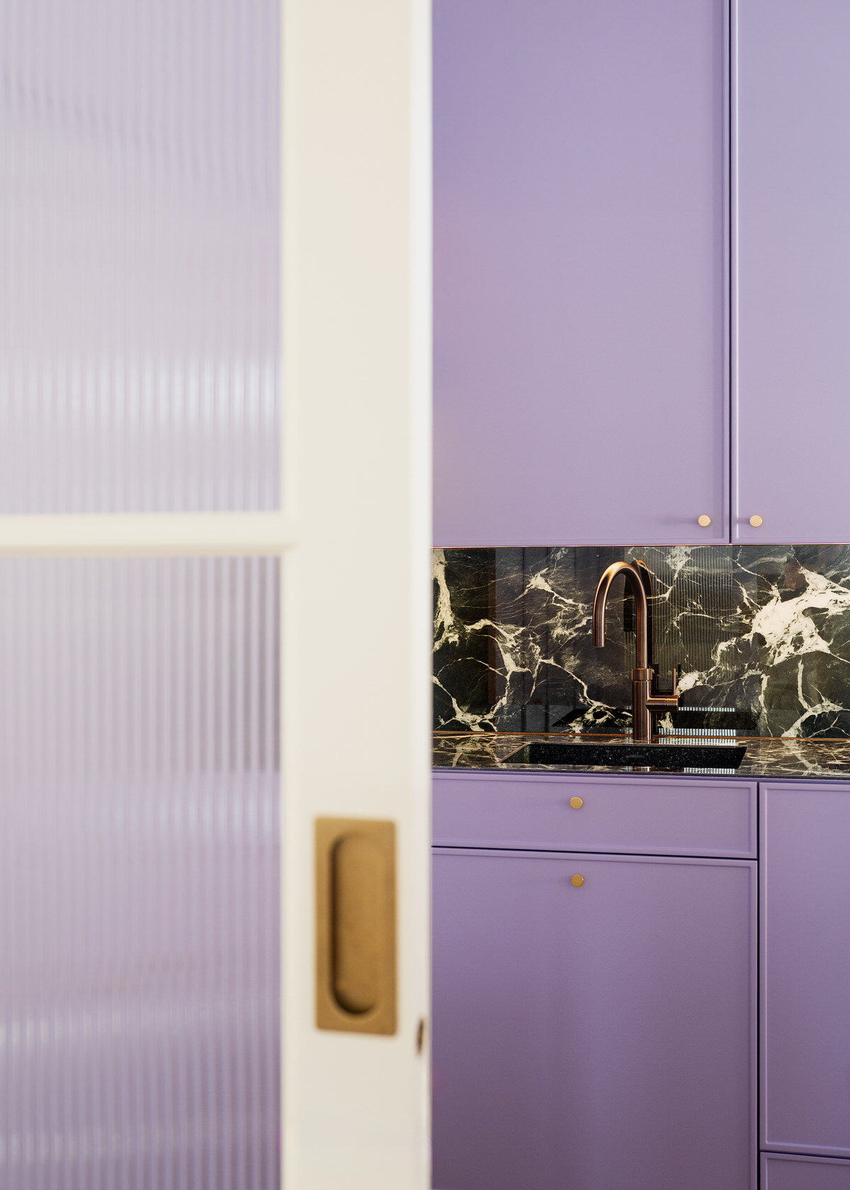 Nahaufnahme der Küchenarmatur, gesehen durch eine halb geöffnete Durchgangsschiebetür.