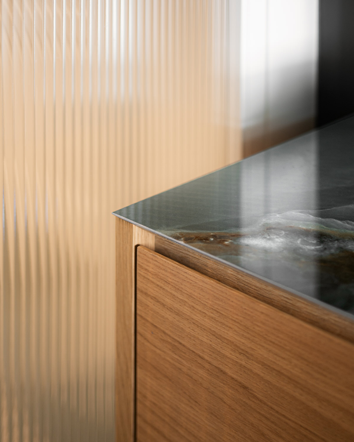 Nahaufnahme eines hölzernen Waschbeckenunterschranks mit einer dünnen Marmorplatte.