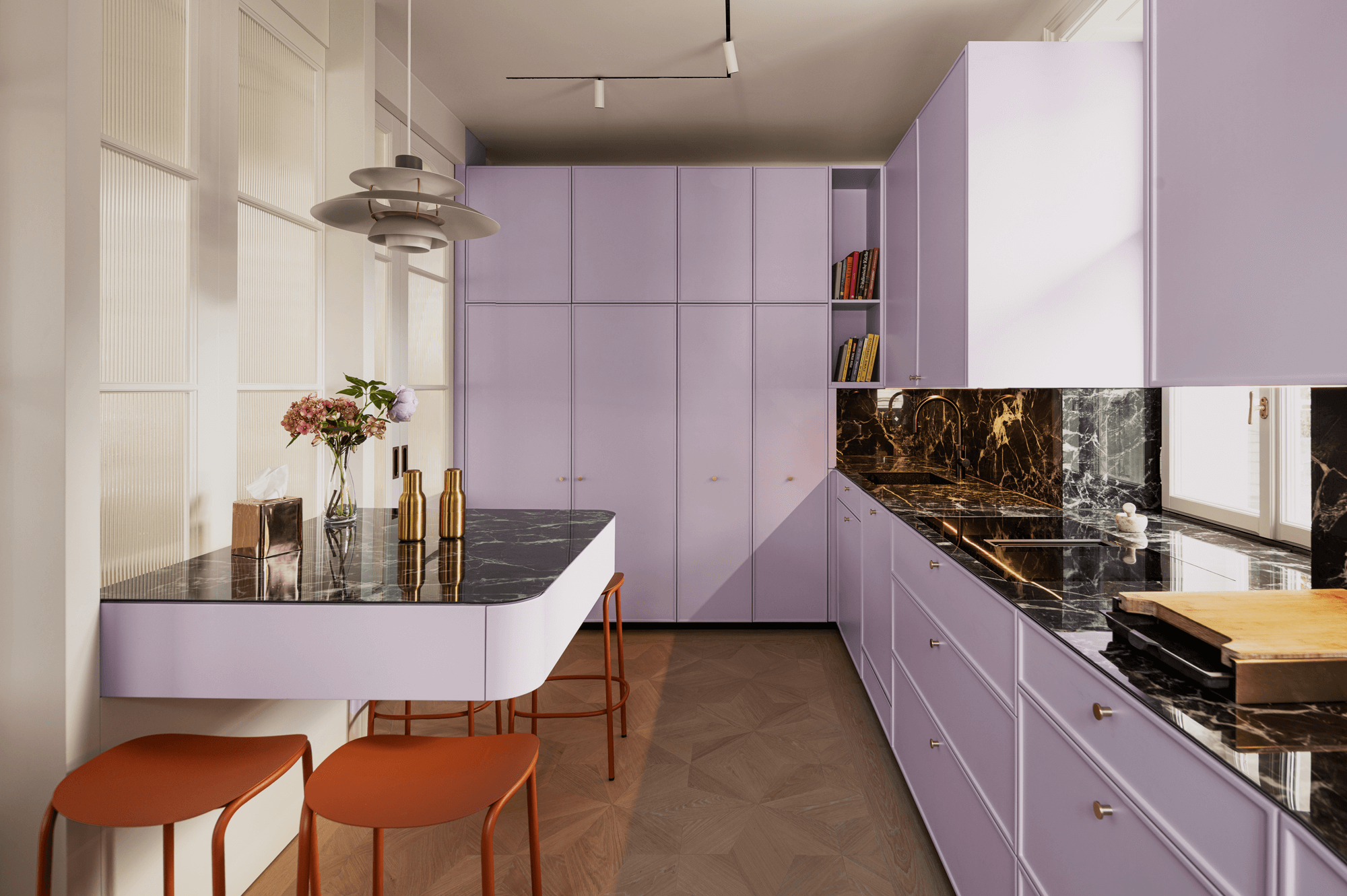 Komplettaufnahme der Küche mit einer Küchenzeile auf der rechten Seite. Links befinden sich eine schwebend wirkende Bar-Sitzgelegenheit und der Durchgang.